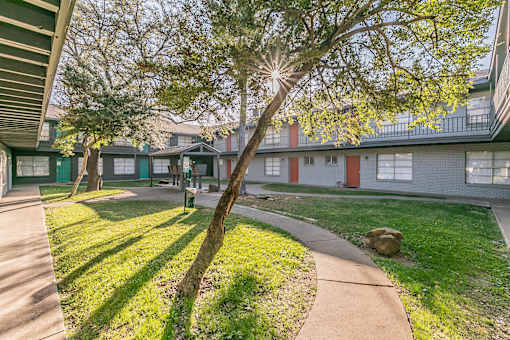 Courtyard walkway with green canopy at Chapel Creek Apartments in Corpus Christi.