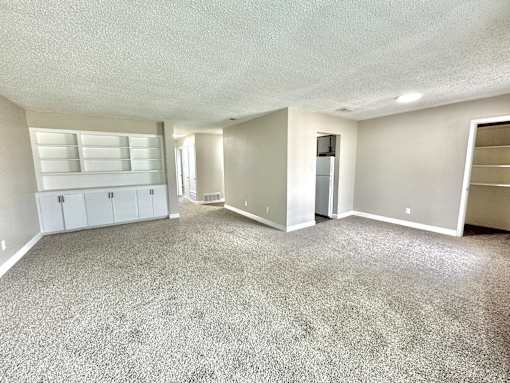 Large living room with grey carpet and bright natural light at Greenbriar Place 55+ Senior Apartments in Corpus Christi.