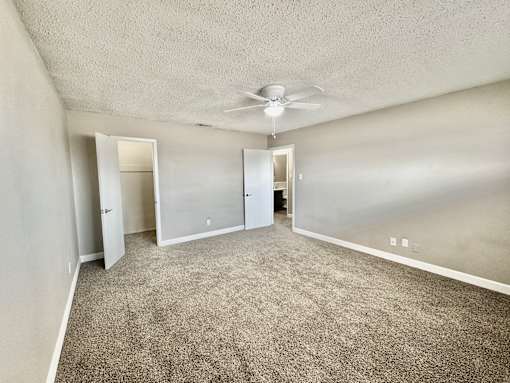 Bedroom with ceiling fan and carpet flooring at Greenbriar Place 55+ Apartments in Corpus Christi.