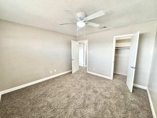 Bedroom with ceiling fan and carpet flooring at Greenbriar Place 55+ Apartments in Corpus Christi.