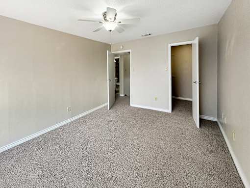 A room with a ceiling fan and carpeted floor.