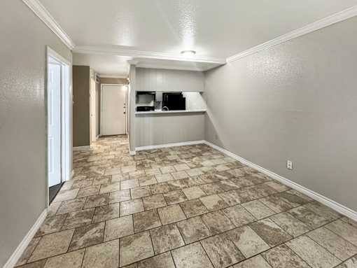 A room with a tiled floor and a small kitchenette.