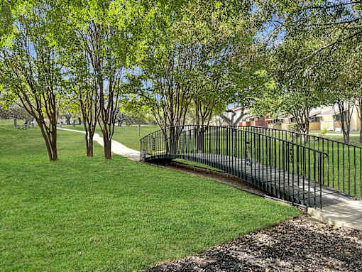 A black metal fence borders a grassy area with trees.