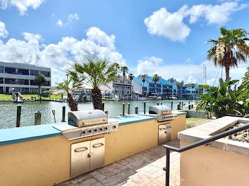 A grill is on a patio next to a pool.