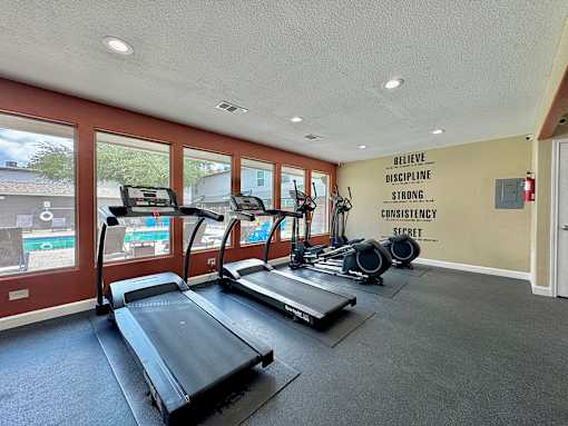 A gym with treadmills and a wall with the words "Believe Discipline Strong Consistency Secret" written on it.