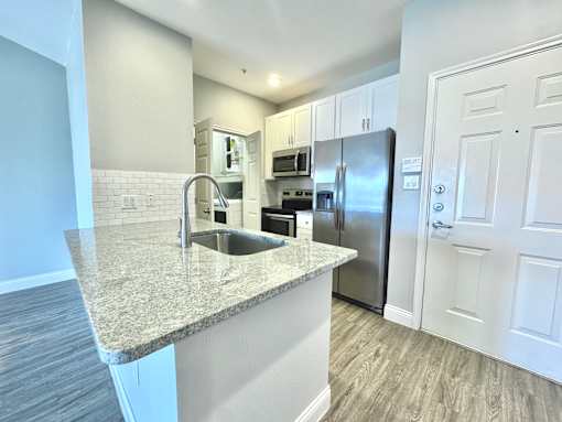 A kitchen with a granite countertop and stainless steel appliances.