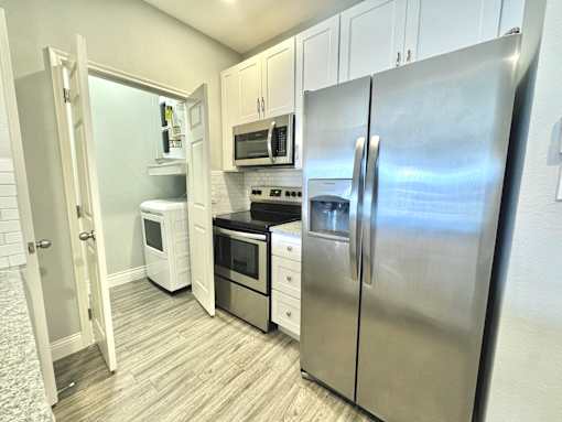 A kitchen with a refrigerator, oven, and microwave.