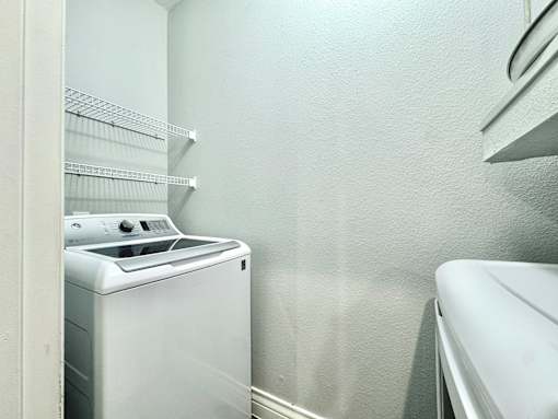 A white dryer is in a laundry room with a white washing machine.