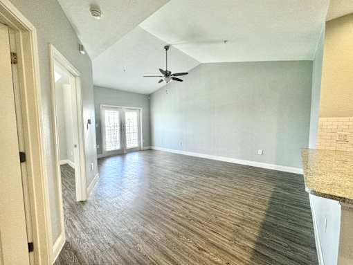 A room with a ceiling fan and wood flooring.