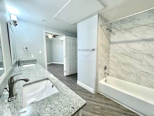 A bathroom with a marble countertop and a white bathtub.