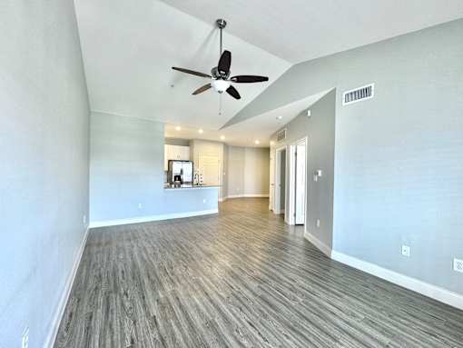 A spacious room with a ceiling fan and wooden flooring.