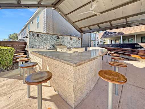 a bar with wooden stools and a grill on a patio