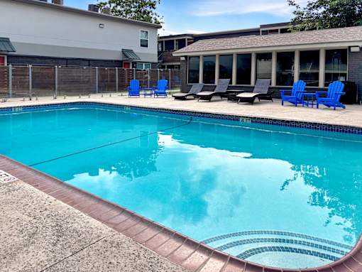 A swimming pool with blue chairs around it.