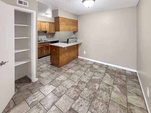 A kitchen with a tile floor and wooden cabinets.