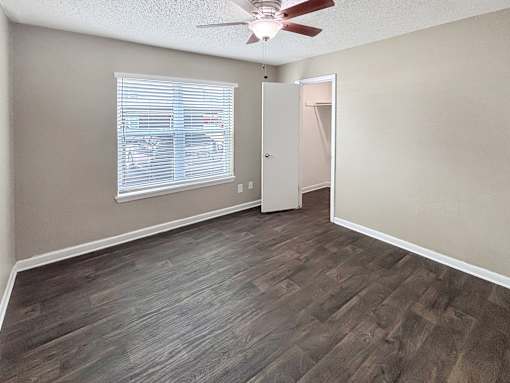 A room with a ceiling fan and a window with blinds.