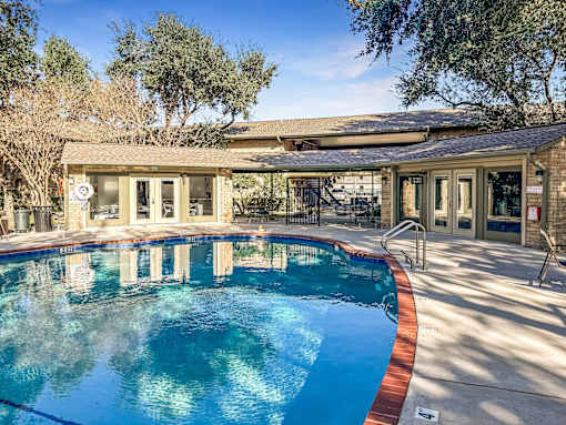 Relaxing swimming pool area at Greenbriar Place 55+ Apartments in Corpus Christi, featuring lounge chairs and landscaped surroundings.