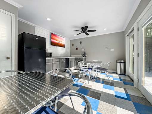 A kitchen with a black fridge and a dining table with chairs.