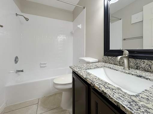 A bathroom with a white toilet and a marble counter top.