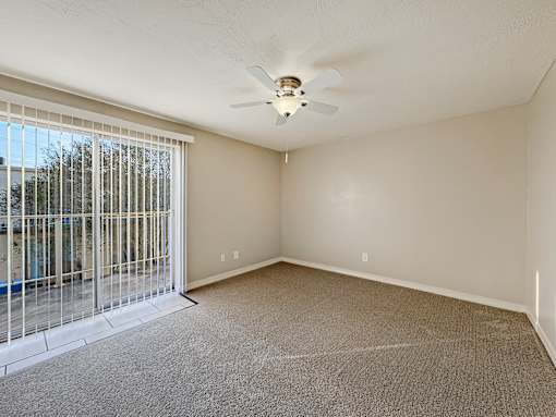 A room with a ceiling fan and a sliding glass door.