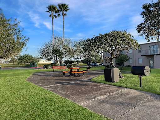 A park with a picnic table and bench in front of a building.