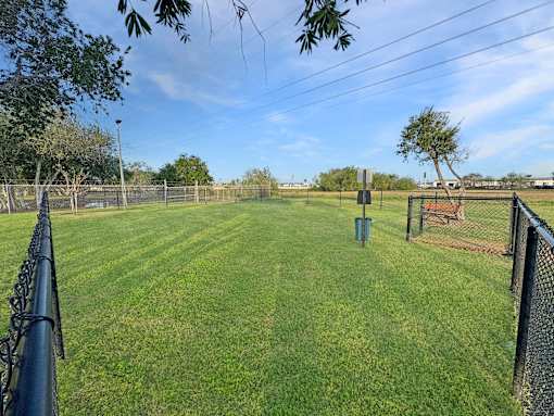 A baseball field with a fence and a trash can.
