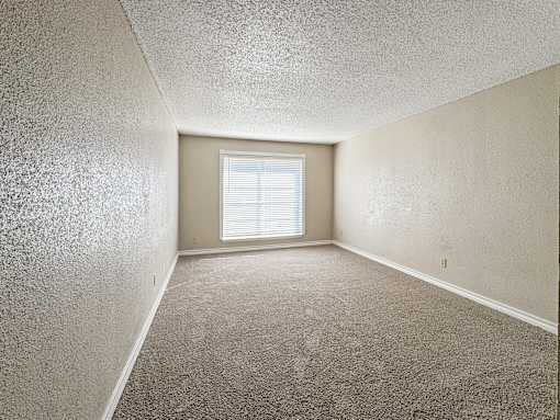Bedroom with carpet flooring and large window – Borders Apartments Brownsville TX