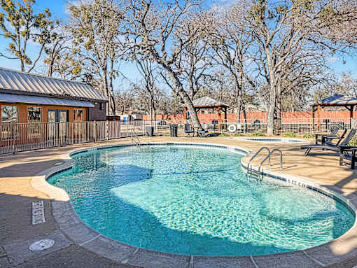 Swimming pool with lounge chairs and landscaping at Verano Oaks Apartments