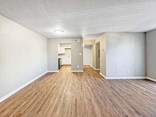 Spacious living room with neutral walls and wood-style flooring at Verano Oaks Apartments in Hurst, TX