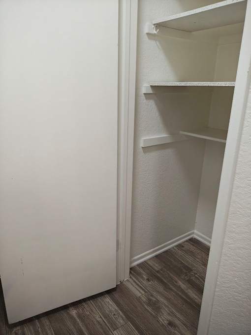 A white bathroom with a towel hanging on the wall at Raintree Apartments, CA 92346