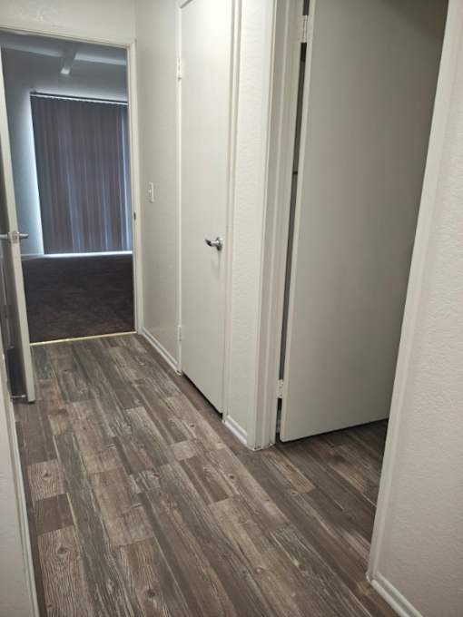 A bedroom with a bed, pillows, and a wooden floor at Raintree Apartments, CA 92346