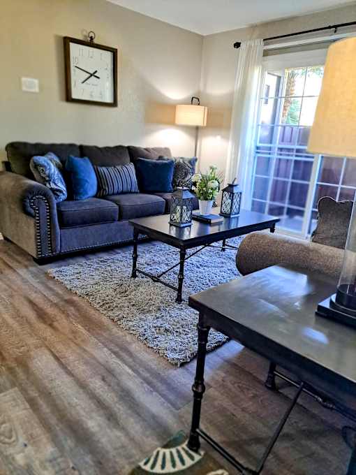A living room with a blue couch and a coffee table at Raintree Apartments, CA 92346
