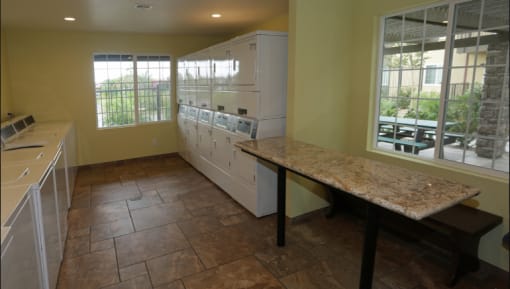 Laundry Center with Machines Next to Folding Counter at Bella Park Apartments, Rialto, CA 92376