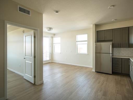 A kitchen with a refrigerator, cabinets, and a doorway leading to another room.