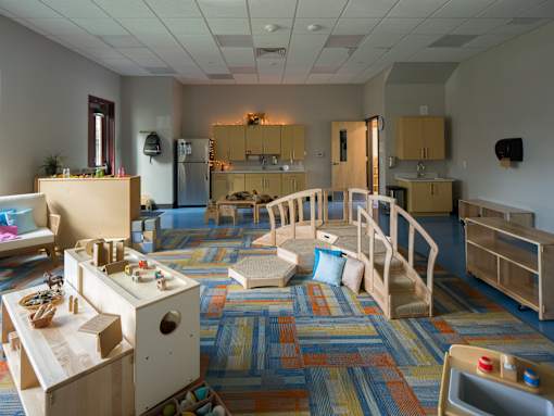 A colorful playroom with a slide and a play kitchen.