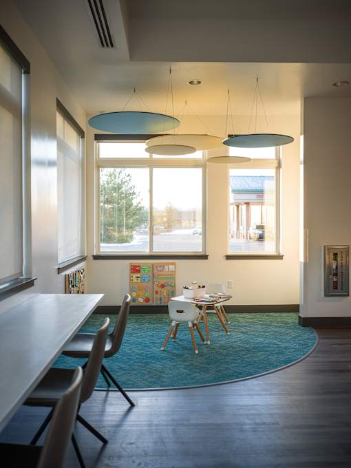 A room with a long table and chairs with a blue rug on the floor.