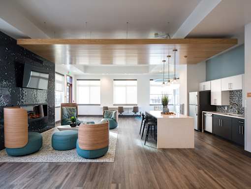 A modern living room with a fireplace and a kitchen area.