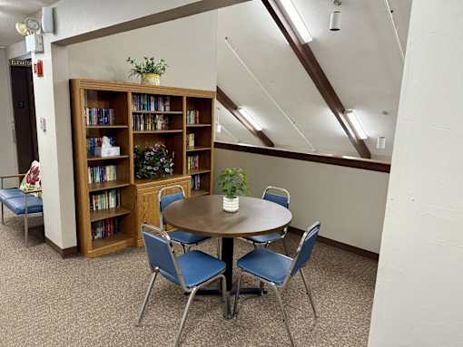 A room with a table, chairs, and a bookcase.