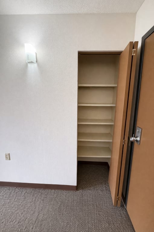 A white wall with a brown door and a light switch.