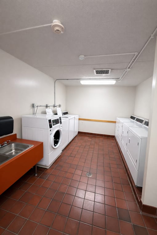 A laundry room with a brown tile floor and white appliances.
