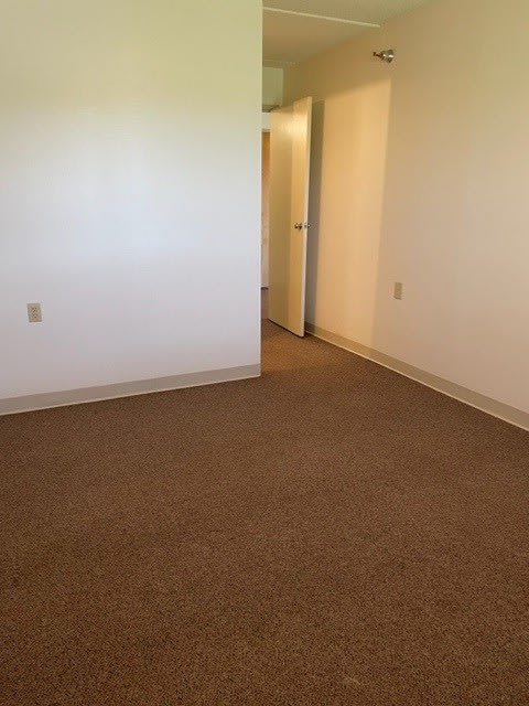 an empty room with a white wall and carpet