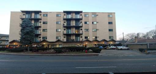 A large apartment building with a parking lot in front.