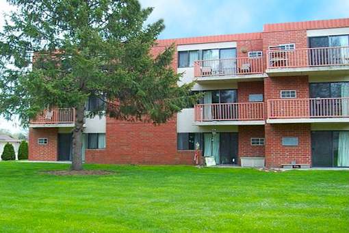 A red brick apartment building with a green lawn in front.