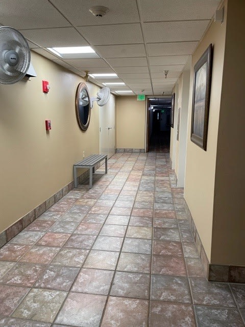 a hallway with a bench and a fan