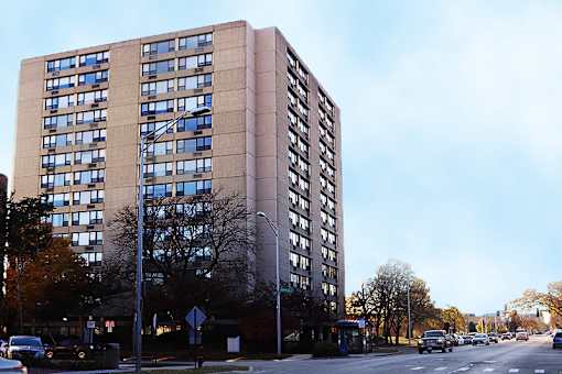 A tall building with many windows is in the background of a street scene.