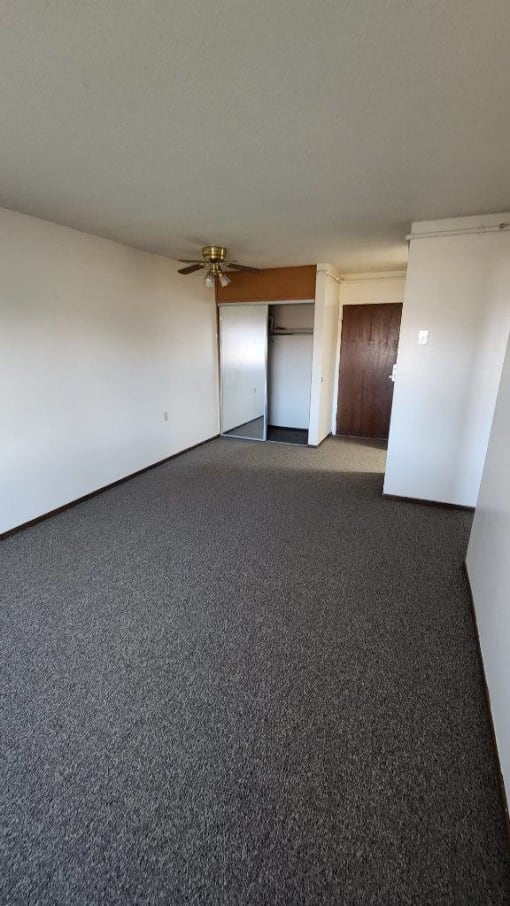 an empty room with a ceiling fan and a door