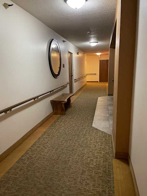 A long hallway with a light on the left and a round mirror on the right.