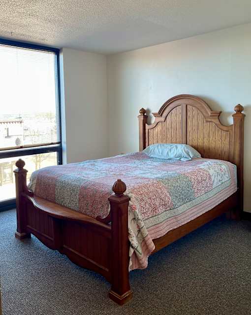 A bed with a wooden headboard and footboard with a striped comforter on top of it.