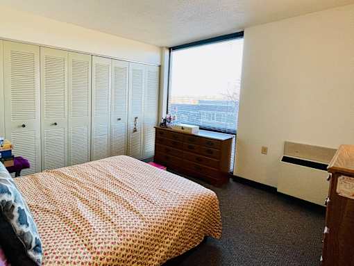 A bedroom with a bed, dresser, and wardrobe.