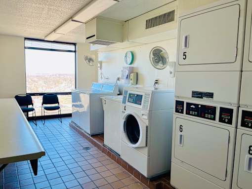 A row of white washing machines are lined up in a laundromat.
