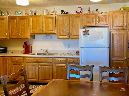 A kitchen with wooden cabinets and a white fridge.